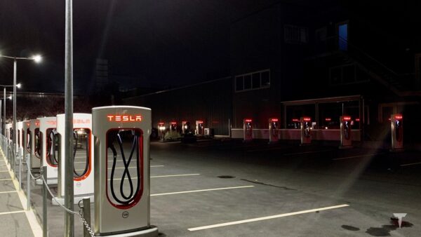 Stazione Tesla Supercharger di notte con una fila di colonnine di ricarica